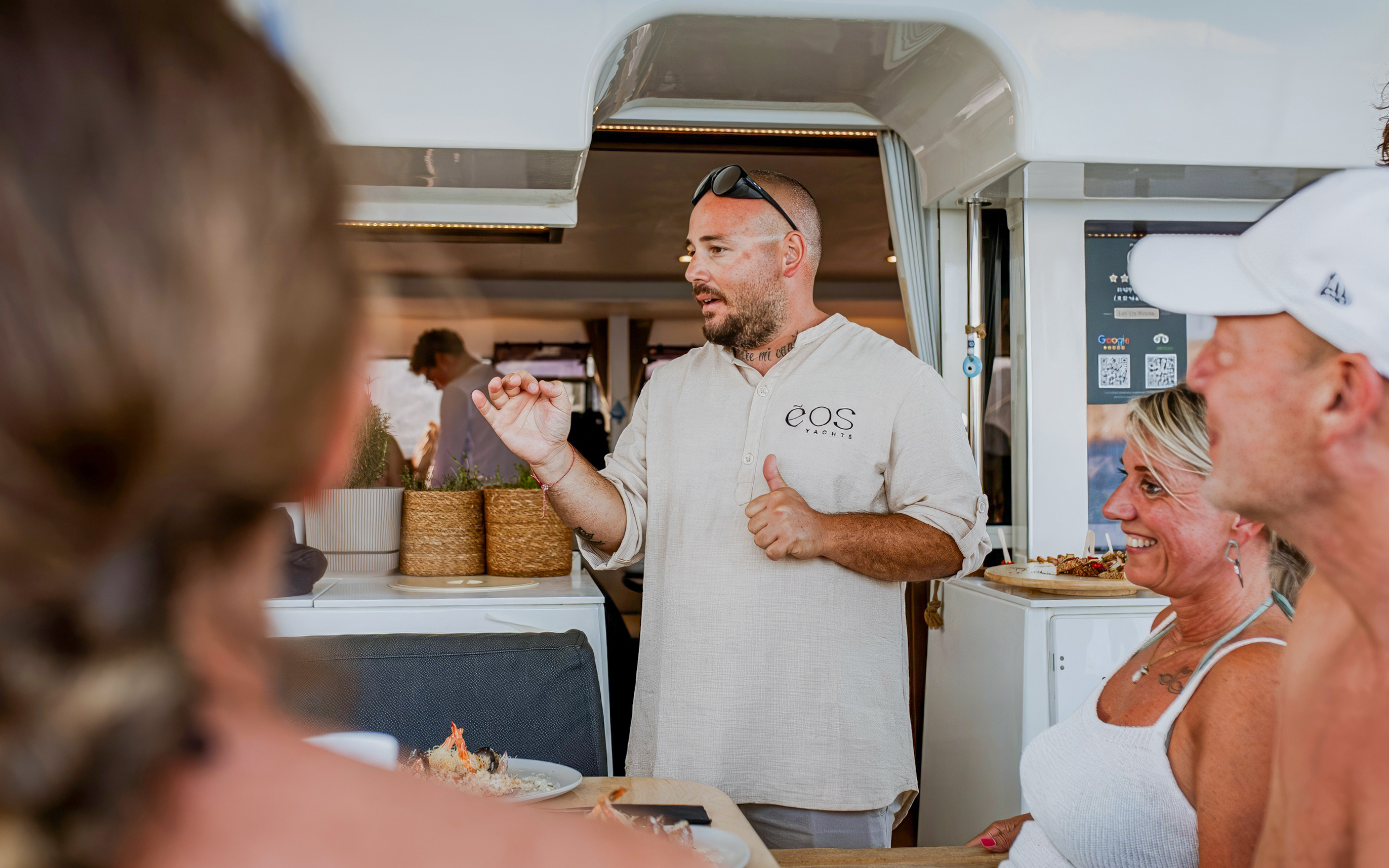 Chef engaging with guests on Heraklion catamaran cruise, showcasing onboard dining experience.
