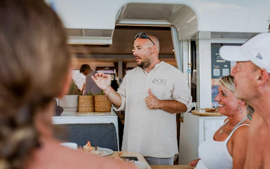Chef engaging with guests on Heraklion catamaran cruise, showcasing onboard dining experience.