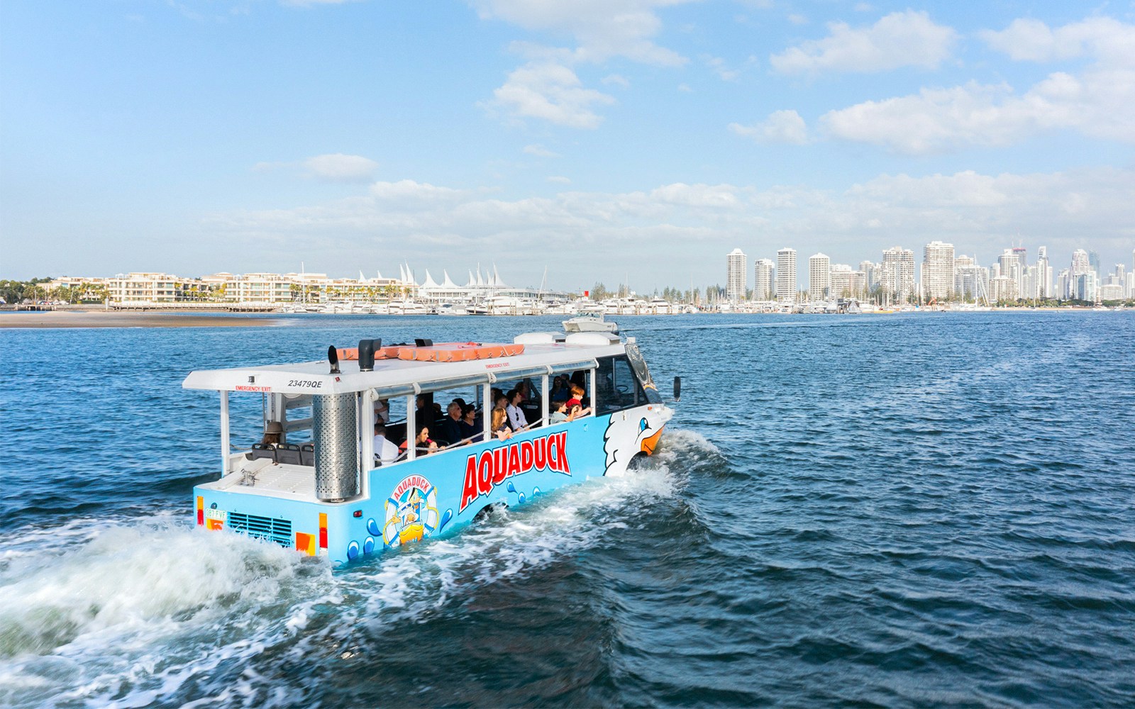 Aquaduck tour vehicle cruising on a river with city skyline in the background.