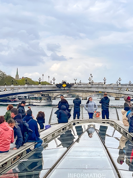 Tourists on a Seine River cruise with Eiffel Tower and Pont Alexandre III in Paris.