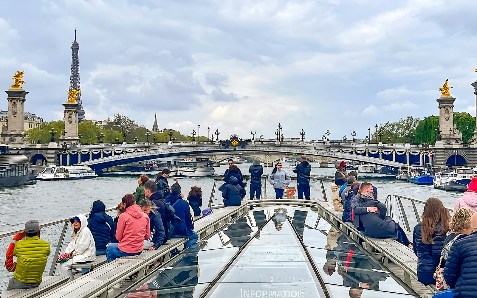 Seine River cruise with tourists viewing the Eiffel Tower in Paris.