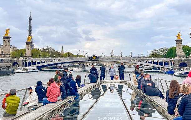 Tourists on a Seine River cruise with Eiffel Tower and Pont Alexandre III in Paris.
