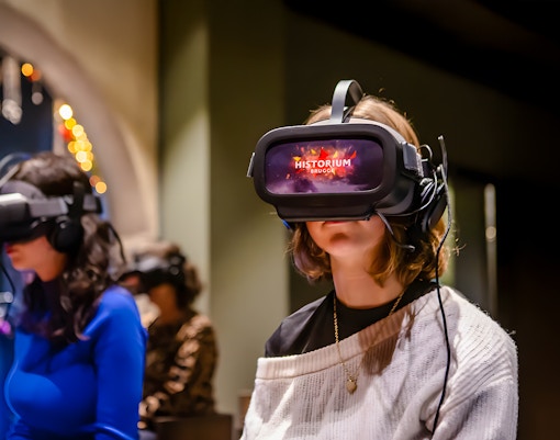 Guest experiencing Historium Bruges VR tour with medieval Bruges backdrop.