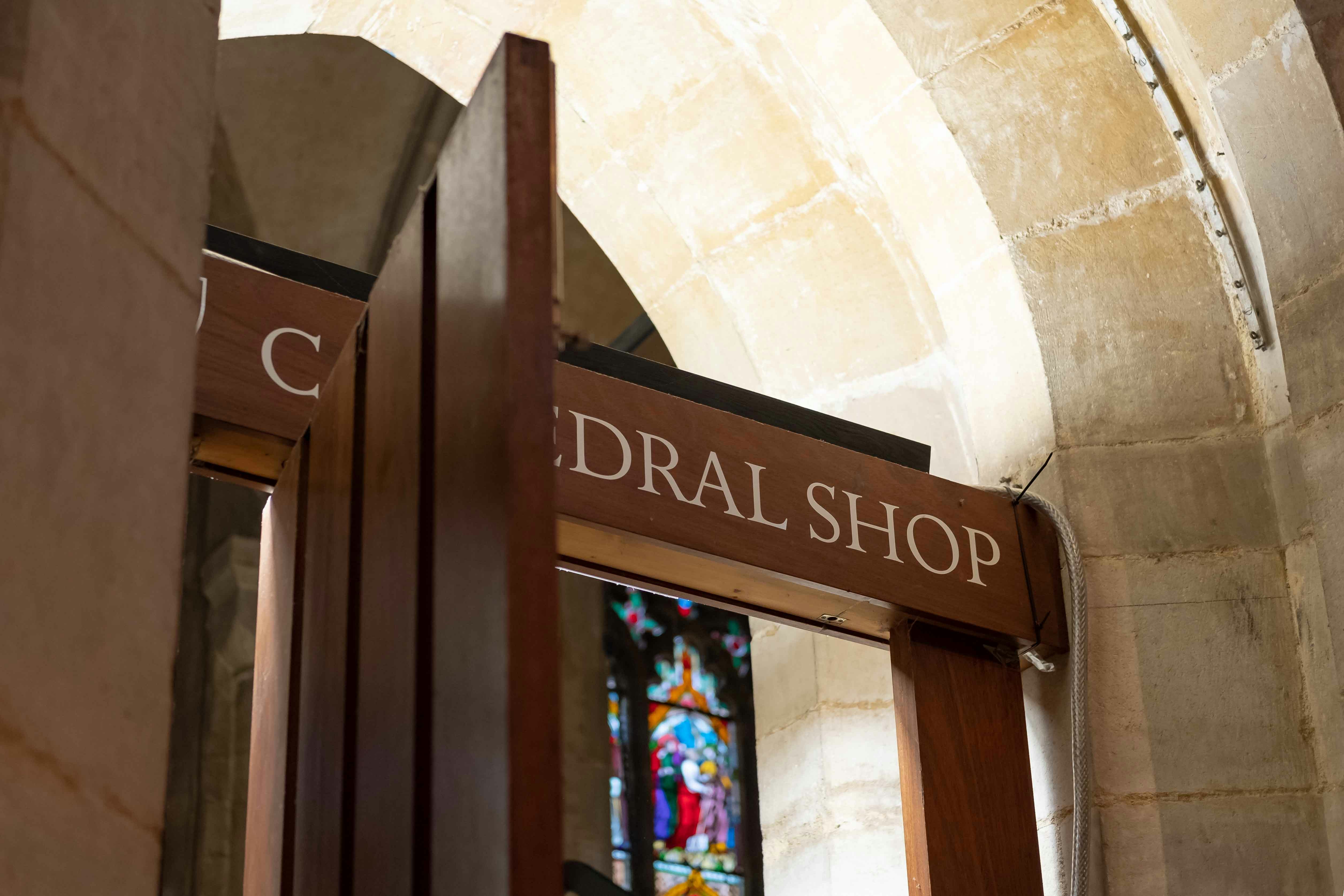 Westminster Abbey shop entrance with stained glass window in background.