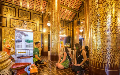Participants listening to a guide inside a decorated temple during Chiang Mai Night Bike Tour.