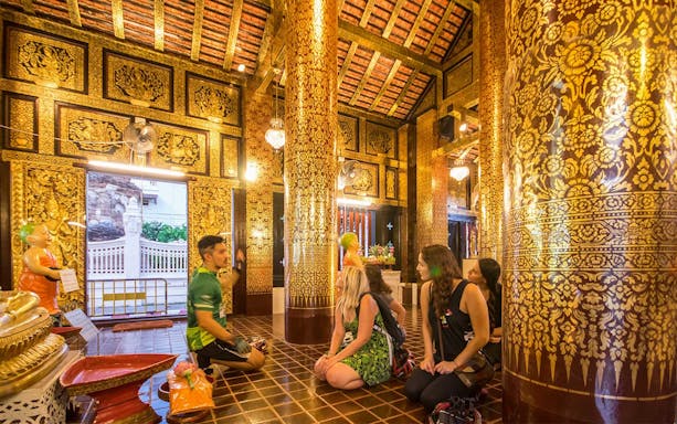 Participants listening to a guide inside a decorated temple during Chiang Mai Night Bike Tour.