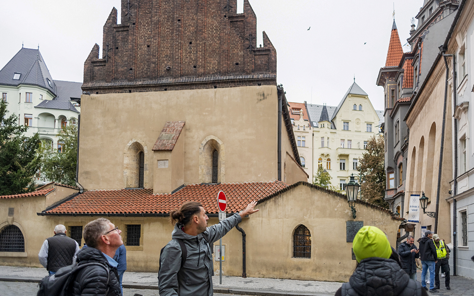 Tour guide leading guests through the Jewish Quarters in Prague, pointing at historical buildings.