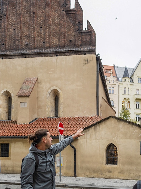 Tour guide leading guests through the Jewish Quarters in Prague, pointing at historical buildings.