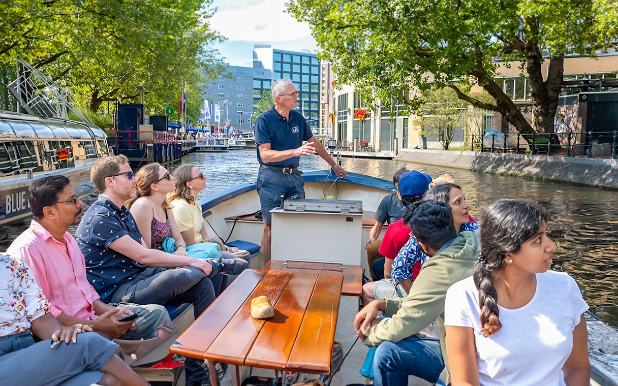 Small group enjoying a canal cruise in Amsterdam on an open boat.