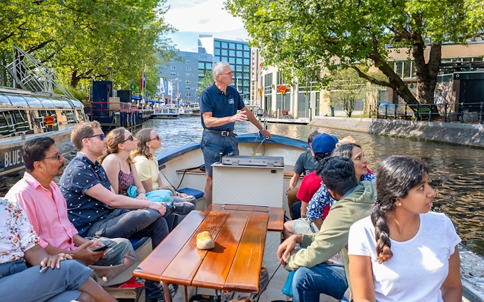 Small group enjoying a canal cruise in Amsterdam on an open boat.