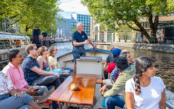 Small group enjoying a canal cruise in Amsterdam on an open boat.