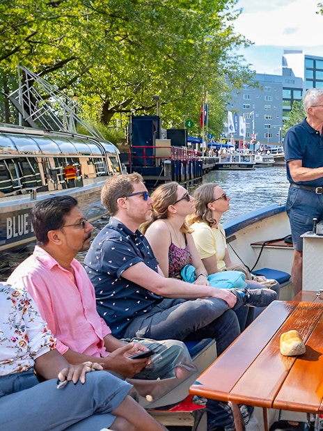 Small group enjoying a canal cruise in Amsterdam on an open boat.