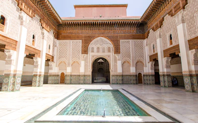 Ben Youssef Madrasa courtyard with intricate tilework and central pool in Marrakech, Morocco.