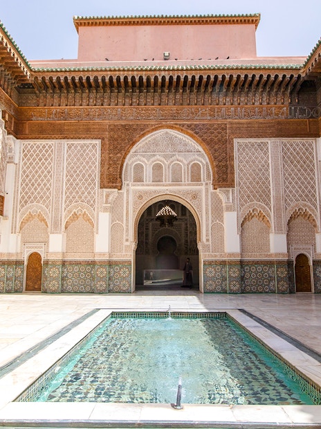 Ben Youssef Madrasa courtyard with intricate tilework and central pool in Marrakech, Morocco.