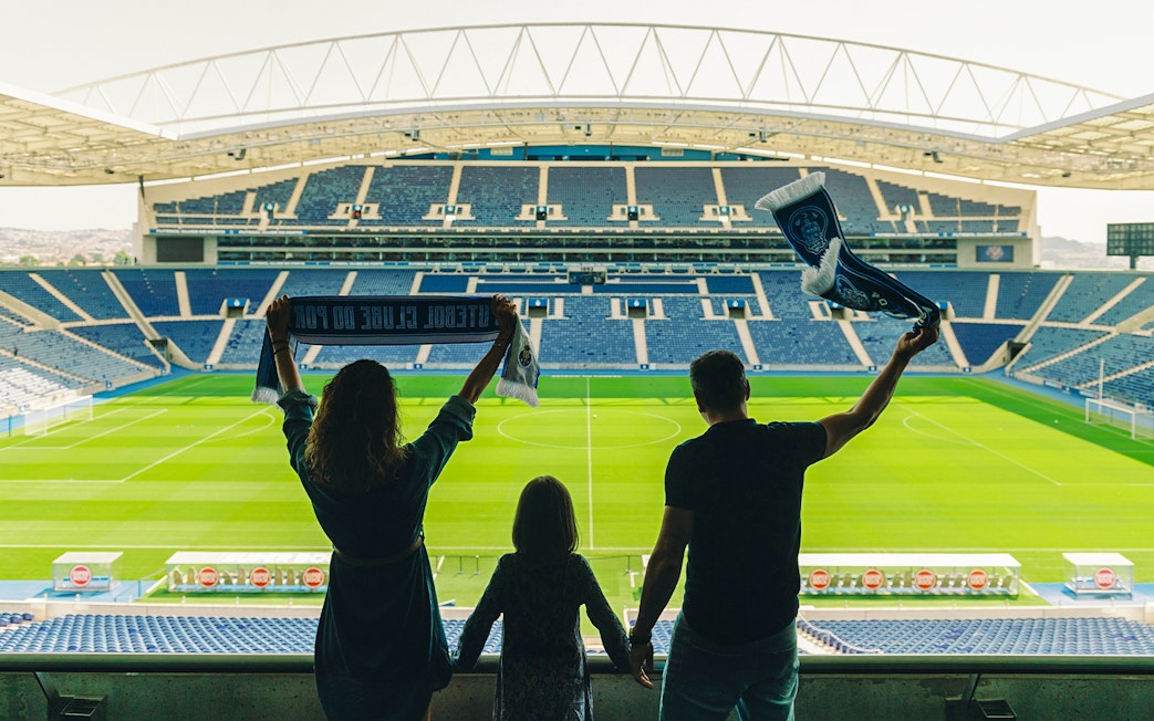Visitors holding scarves in FC Porto stadium overlooking the field.