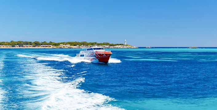 Rottnest Express ferry creating a wake, with Rottnest Island and lighthouse visible in the distance.