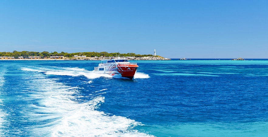 Rottnest Express ferry creating a wake, with Rottnest Island and lighthouse visible in the distance.
