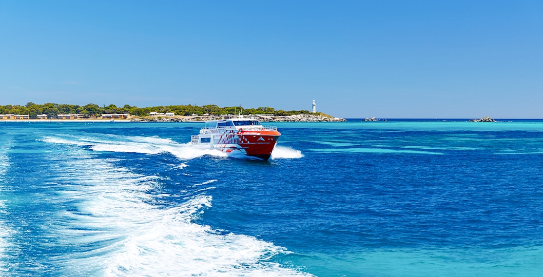 Rottnest Express ferry creating a wake, with Rottnest Island and lighthouse visible in the distance.