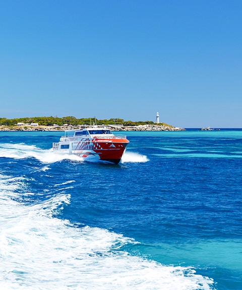 Rottnest Express ferry creating a wake, with Rottnest Island and lighthouse visible in the distance.