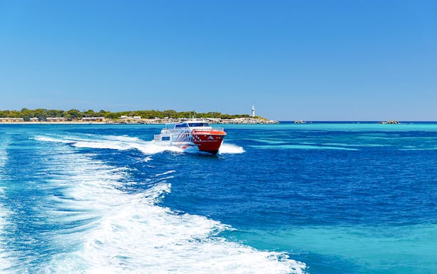 Rottnest Express ferry creating a wake, with Rottnest Island and lighthouse visible in the distance.
