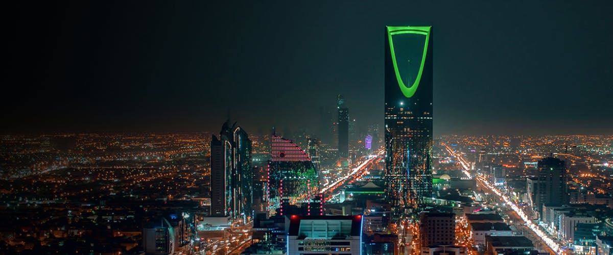 Riyadh cityscape at night featuring the illuminated Kingdom Centre Tower.