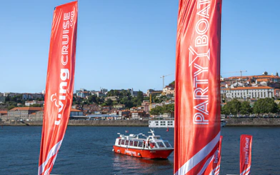 Party boat on Douro River with Porto cityscape in the background.