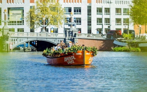 Guests enjoying Aperol Spritz Cruise on Amsterdam canal with bridge in background.