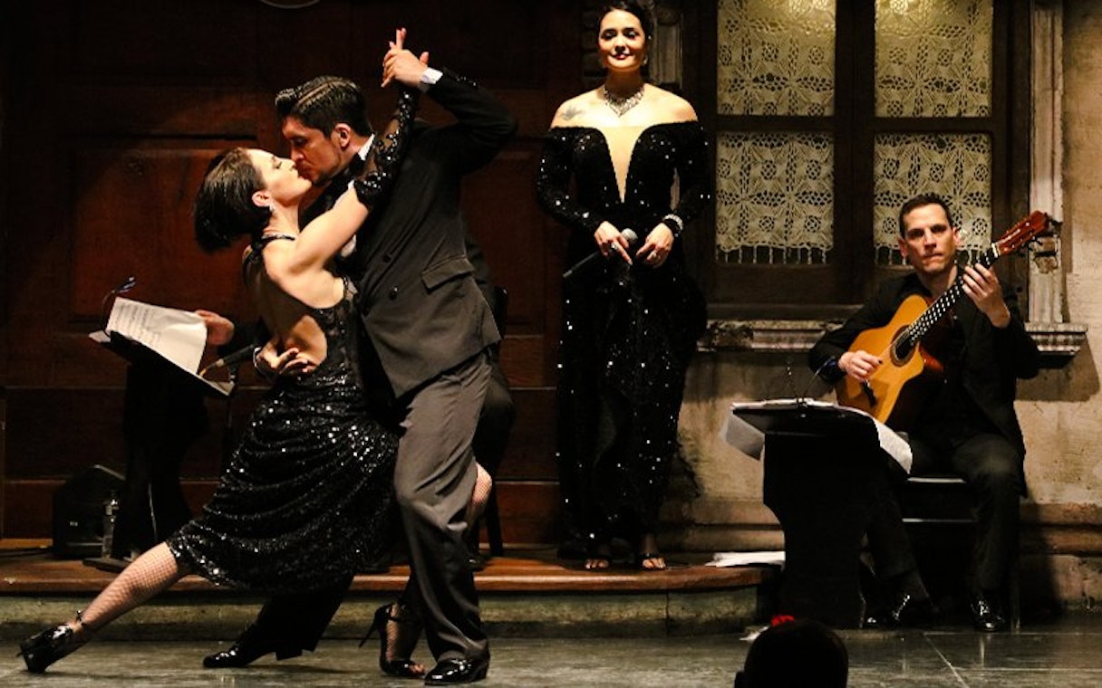 Tango dancers performing at Aljibe Tango Show in Buenos Aires with live musicians.