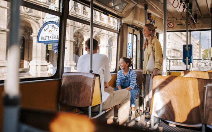 Tourists enjoying a tram ride in Vienna, with views of historic architecture outside.