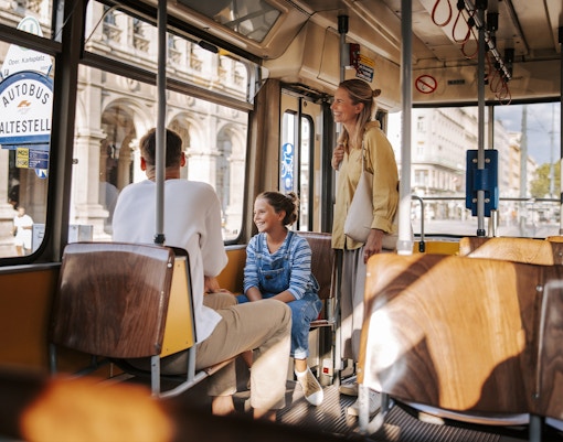 Tourists enjoying a tram ride in Vienna, with views of historic architecture outside.