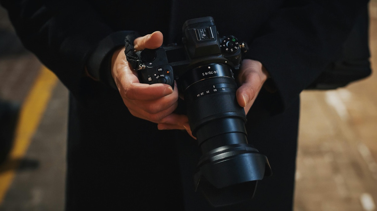 Photographer holding a modern mirrorless camera close-up.