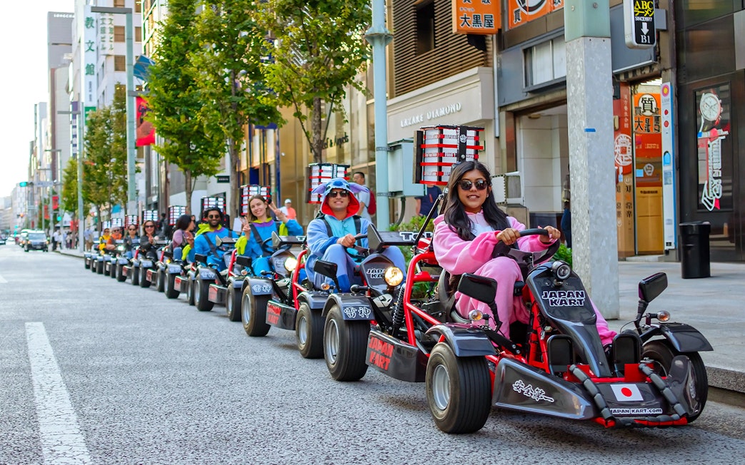 People driving go-karts in costumes on Asakusa streets during a 60-minute tour.
