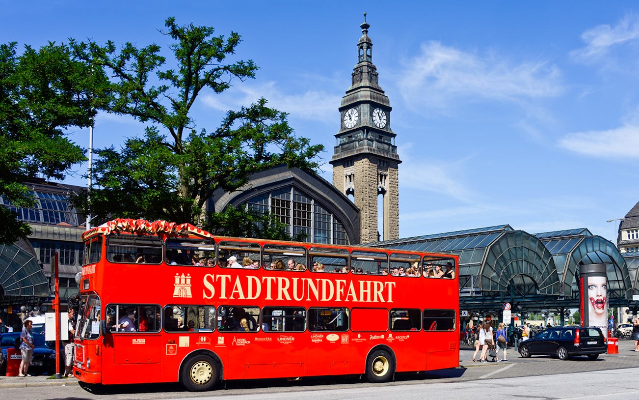 Red double-decker bus in front of Hamburg's St. Michael's Church during city tour.