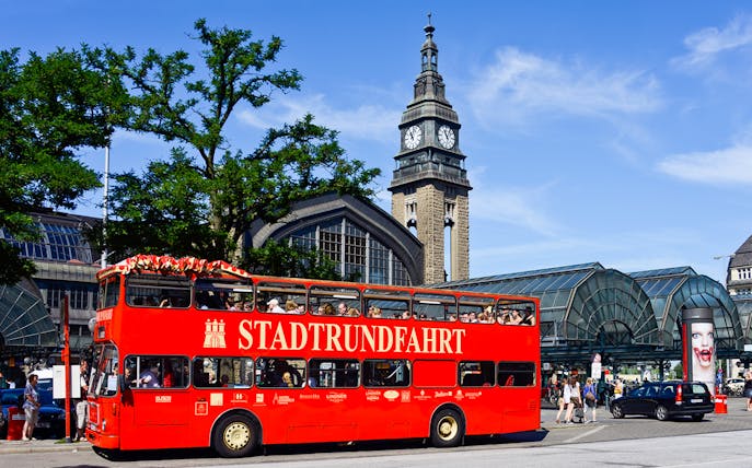 Red double-decker bus in front of Hamburg's St. Michael's Church during city tour.