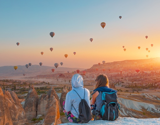 Hot air balloons over Cappadocia landscape, Turkey, highlighting tour timings.