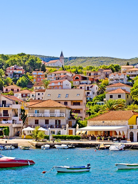 Boats docked at the Port of Jelsa, Hvar island, Croatia, with hillside houses in the background.