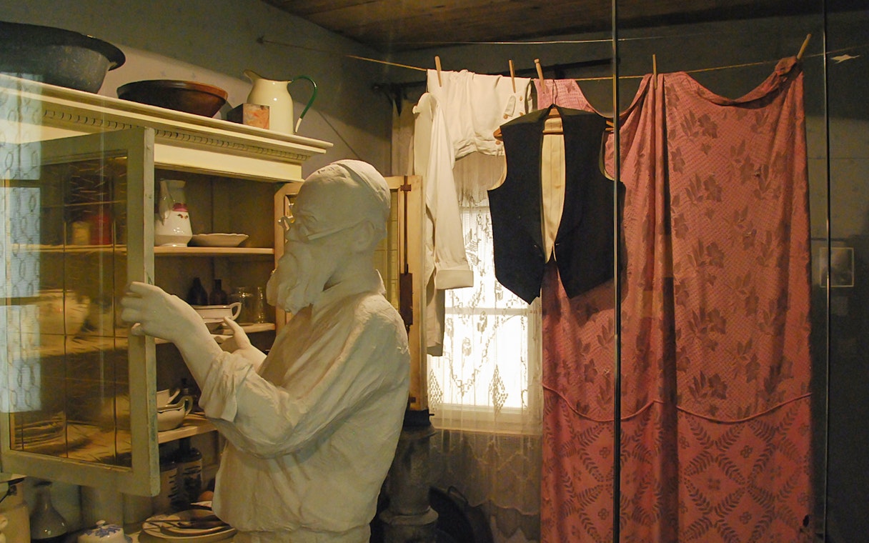 Mannequin in Schindler's Factory Museum kitchen scene with vintage clothing and dishes.