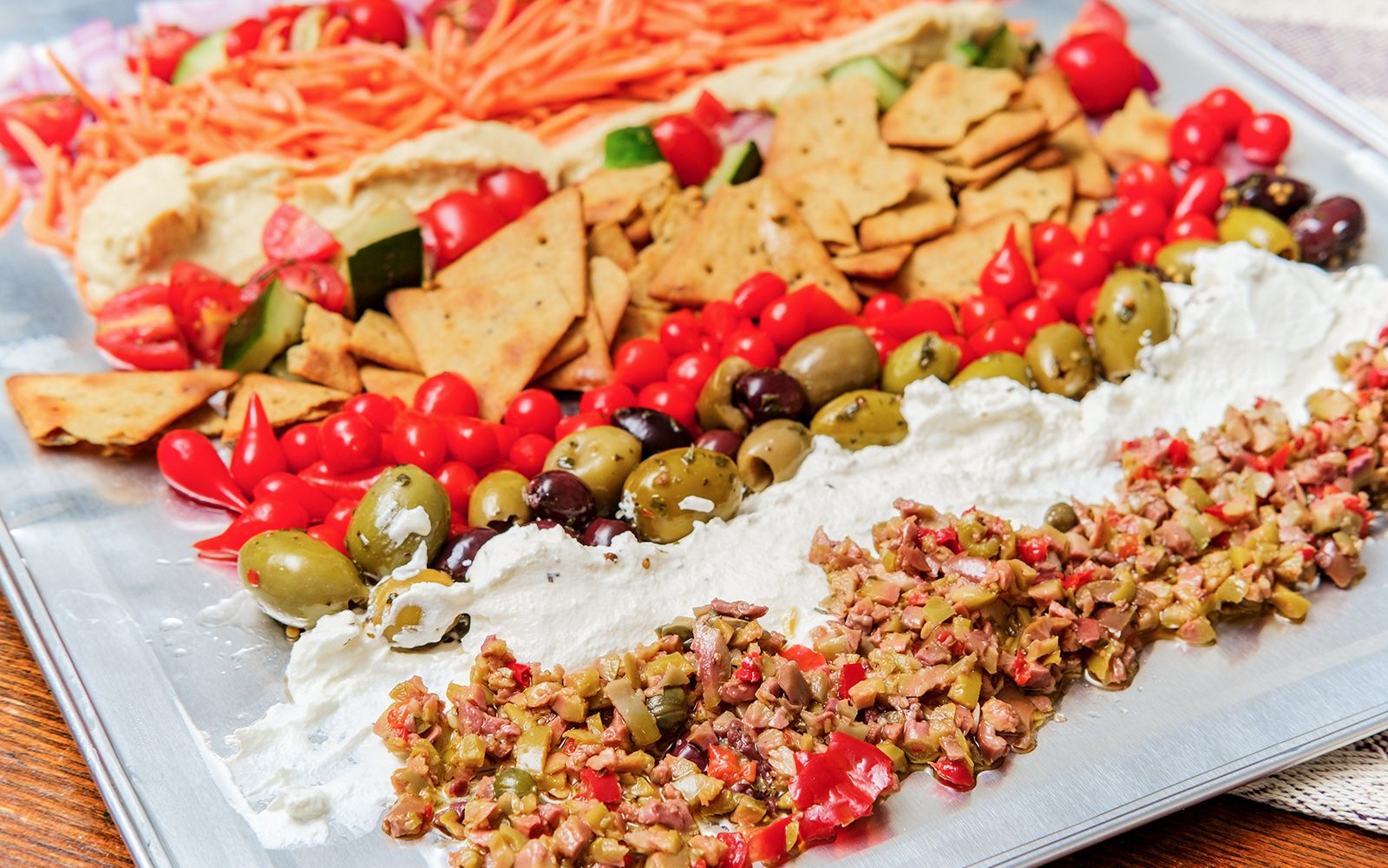 Greek olive hummus platter with pita, cherry tomatoes, and assorted olives.