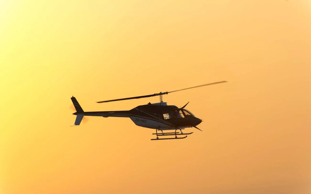 Helicopter flying over Victoria Falls at sunset during scenic tour.