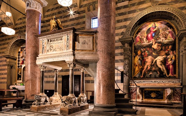 Volterra Cathedral interior with ornate pulpit and religious artwork.