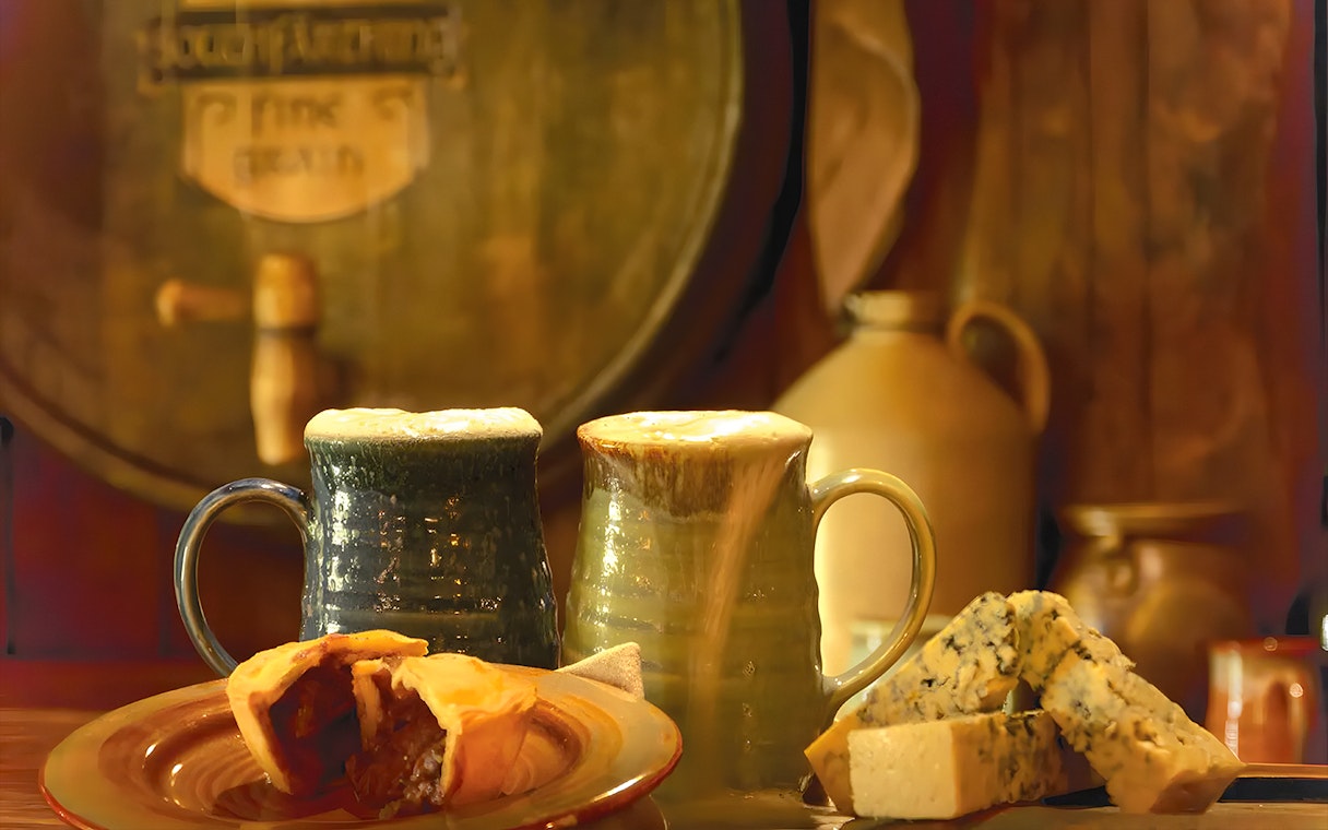 Mugs of ale with pie and cheese at Hobbiton Movie Set, New Zealand.