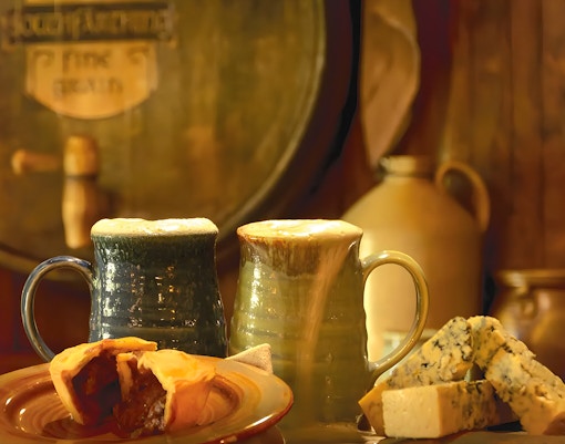 Mugs of ale with pie and cheese at Hobbiton Movie Set, New Zealand.