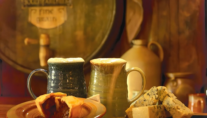Mugs of ale with pie and cheese at Hobbiton Movie Set, New Zealand.