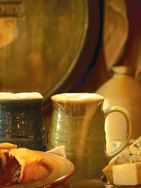 Mugs of ale with pie and cheese at Hobbiton Movie Set, New Zealand.