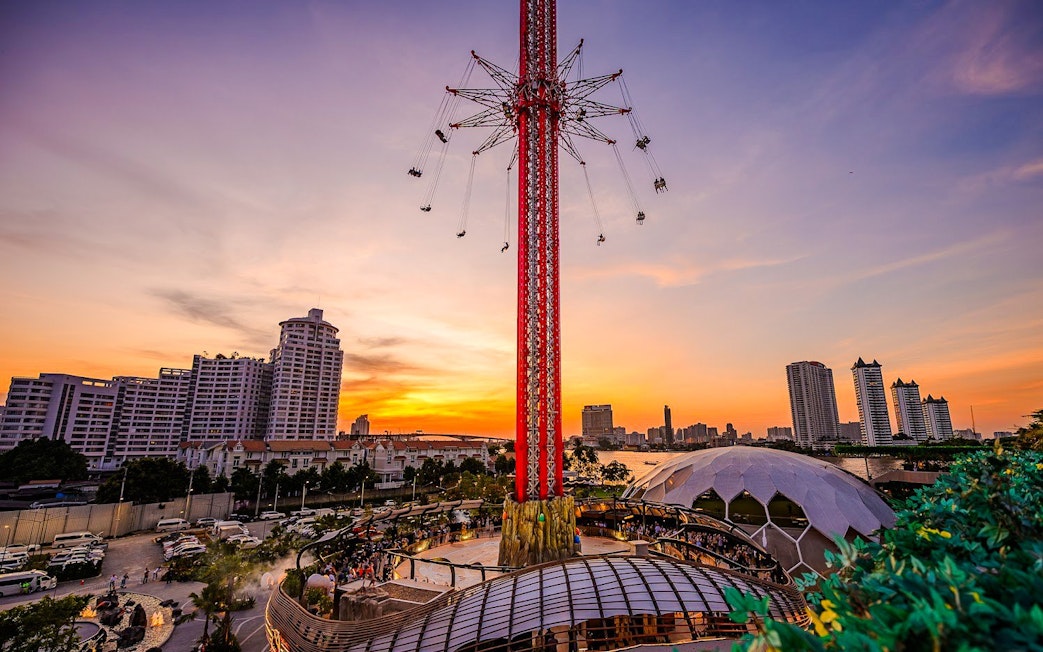 SkyFlyers ride at Asiatique Bangkok with sunset skyline in the background.