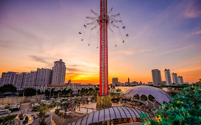 SkyFlyers ride at Asiatique Bangkok with sunset skyline in the background.