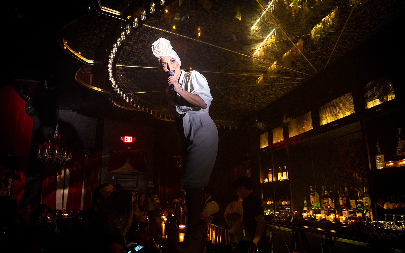 Performer on bar counter during Miss Behaves: Maverick's Variety Show in dimly lit venue.