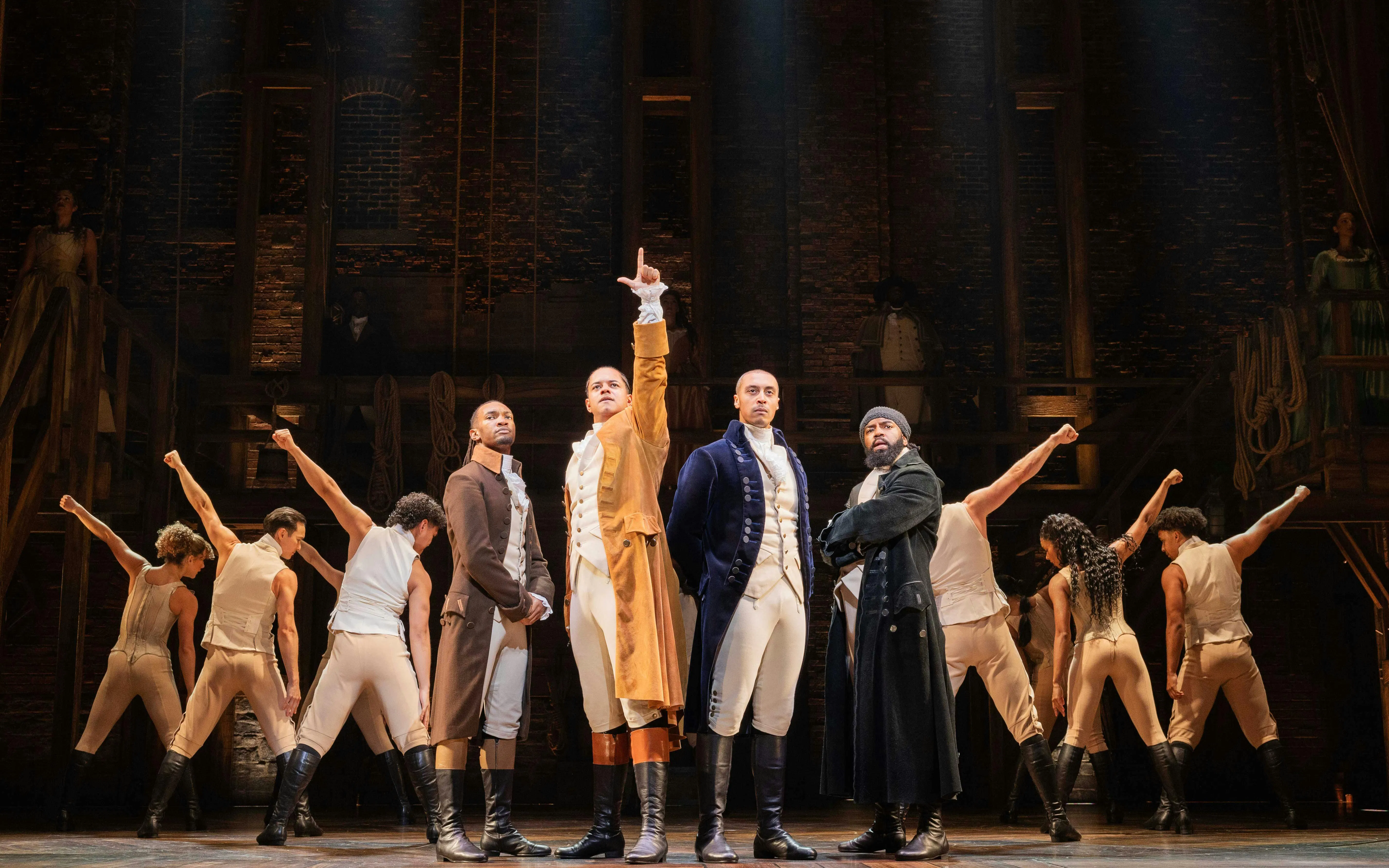 Cast performing Hamilton on West End stage, actors in period costumes.