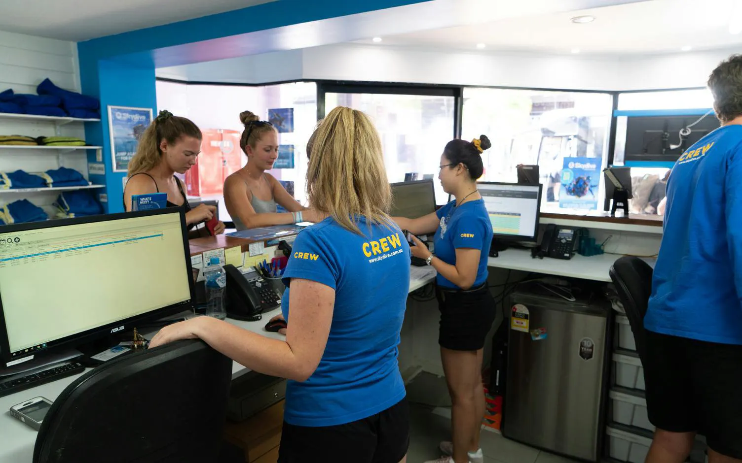 Staff assisting customers at Airlie Beach Tandem Skydive booking desk.