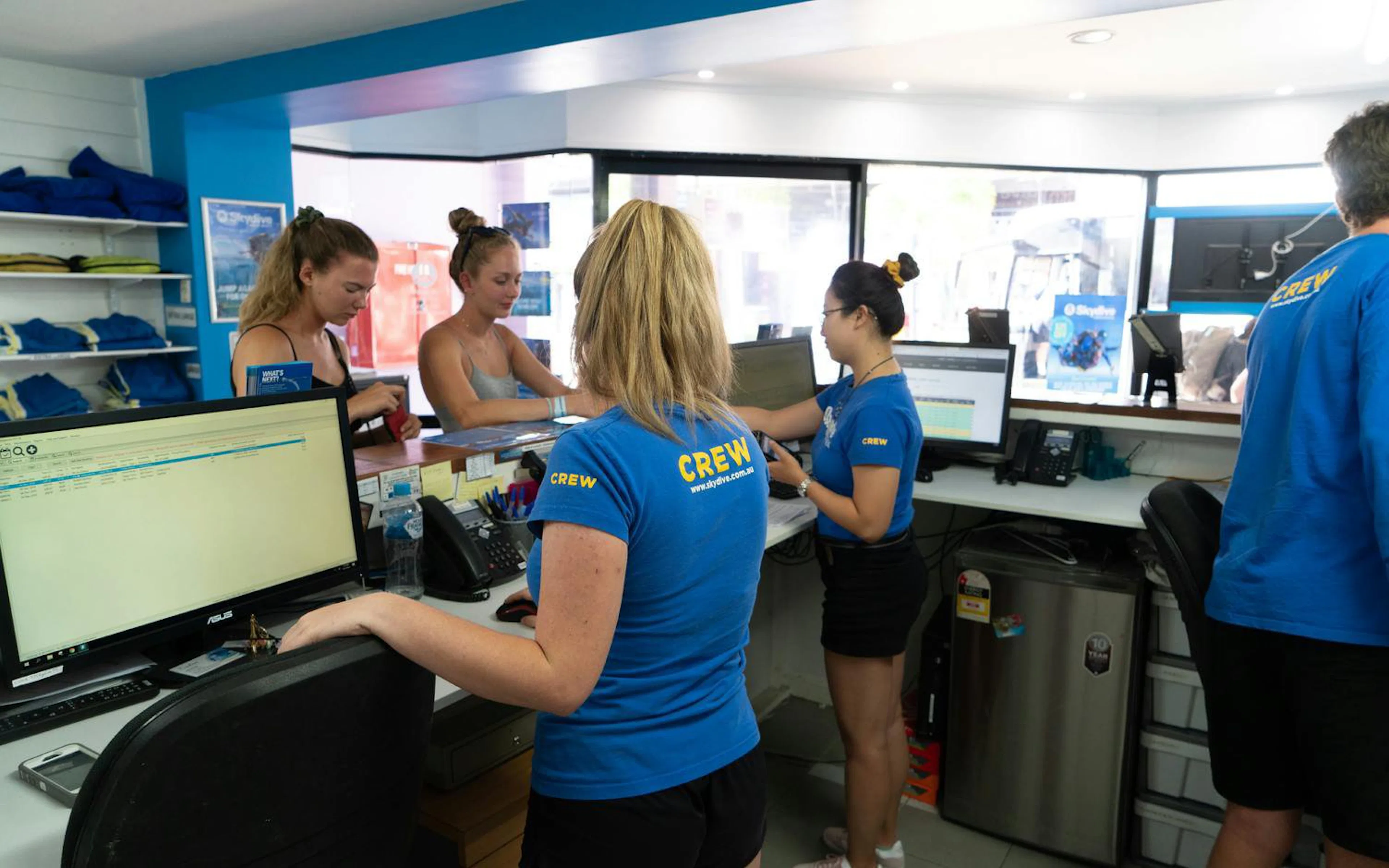Staff assisting customers at Airlie Beach Tandem Skydive booking desk.